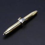 A gold-colored pen with a shiny metallic surface, featuring a modern and stylish design, resting on a dark background. Perfect for writing, gift, or desk decor.