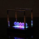 A modern Newton's Cradle with glowing LED spheres, demonstrating momentum transfer and energy conservation in a visually appealing way.