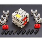 Interlocking plastic gear puzzle with red, yellow, and gray pieces, assembled into a cube, surrounded by additional parts on a black background.