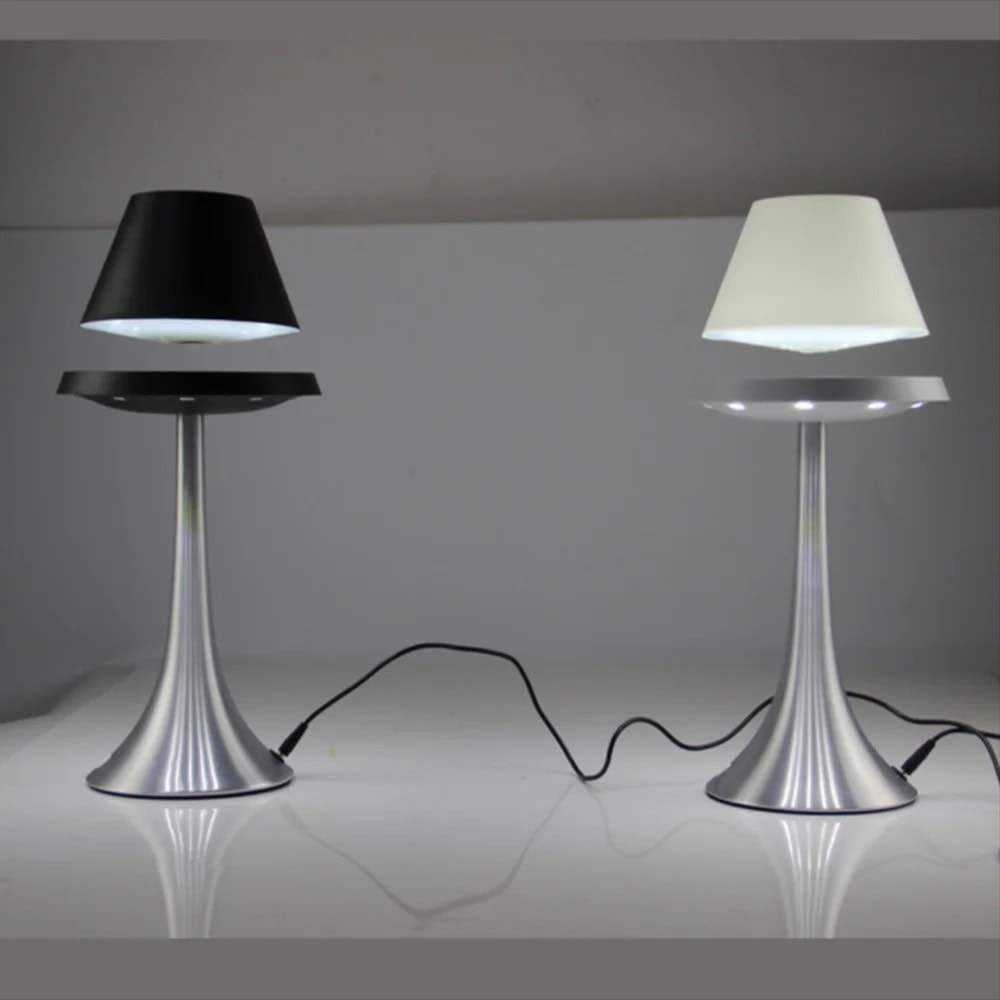 Modern dual-tone table lamps with sleek metallic bases and contrasting black and white lampshades, connected by a power cord, on a minimalist white surface. Levitating Lampshade Lamp - Image 1
