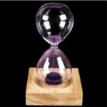 Elegant sand timer with purple sand flowing through glass bulbs, mounted on a wooden base, ideal for educational and decorative purposes.