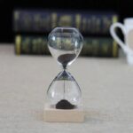 Classic glass hourglass with black sand, used for science experiments, educational demonstrations, and as a stylish decor piece.