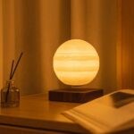 A glowing moon-shaped lamp resting on a wooden base, creating a cozy ambiance in a modern interior setting.