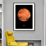 A framed poster of Mars, showcasing its reddish surface with dark patches, hung on a modern gray wall in a contemporary interior setting.