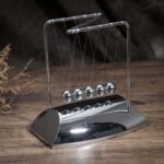 Newton's Cradle metal ball toy for science demonstrations and educational purposes. Perfect for illustrating physics principles like momentum and energy transfer.