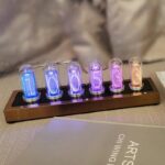 Nixie tube clock showing illuminated numbers 1, 0, 0, 5, 3, 3 in vibrant colors on a wooden base.