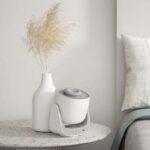 Ultrasonic essential oil diffuser on a bedside table with a white vase and dried pampas grass, creating a calming and modern decor setting.