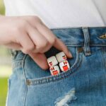 Puzzle cube with red and white design tucked into a jeans pocket, showcasing a fun and educational science-themed accessory.