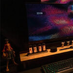 High-resolution image of a modern computer workspace featuring a vibrant, colorful digital screen, a mechanical keyboard with backlit keys, and decorative elements including small animal figurines on.