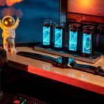 Modern science gadget with glowing tubes and smartwatch on wooden desk, illuminated by ambient lighting, showcasing innovative educational and decorative tech.