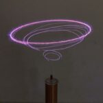 A plasma globe displaying colorful purple and pink electrical arcs forming a ring pattern, demonstrating electromagnetic phenomena.
