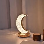 Elegant moon-shaped lamp with intricate floral patterns, glowing softly on a gold base, perfect for bedroom decor or as a night light.
