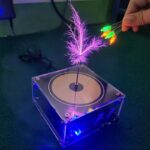 A magnetic levitation device with colorful LED lights, showcasing a floating feather and glowing wires, demonstrating magnetic and electrical principles for educational purposes.