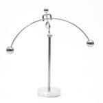 A metal magnetic balance with two spherical weights hanging from a curved metal arm, illustrating magnetic forces and equilibrium principles.