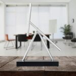 Modern metallic science sculpture with geometric design on wooden surface.