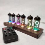 Vintage-style Nixie tube clock displaying numbers with colorful glow, placed on a wooden base with remote control nearby, ideal for science decor and educational purposes.