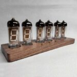 Nixie tube clock displaying time with vintage-style glass tubes on a wooden stand.