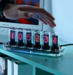 Modern digital nixie tube clock displaying the time 10:52:34 with colorful glowing tubes on a desk. Perfect for science enthusiasts and educational decor.