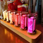 Colorful neon Tesla coil science display with glowing tubes on wooden base, showcasing electrical phenomena and vibrant lighting effects.