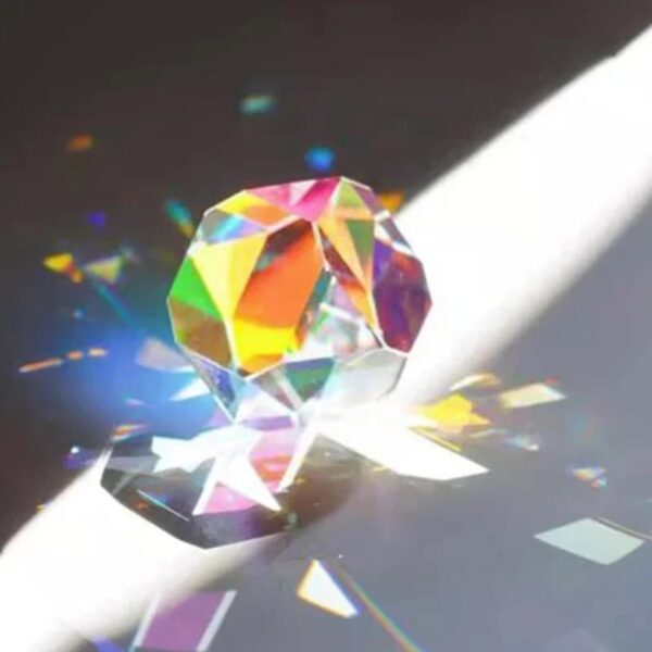 Brightly colored crystal prism reflecting light and creating rainbow patterns on a surface. Perfect for science experiments, educational toys, and decorative science decor.