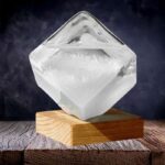 Transparent ice cube sculpture balanced on a wooden base, showcasing clarity and craftsmanship, perfect for science decor and educational displays.