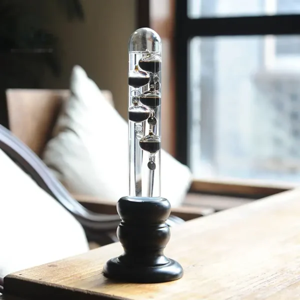 Vintage Newton's Cradle desktop toy with metal balls in a glass tube, demonstrating physics principles.