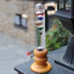 A colorful Newton's Cradle with glass spheres and a wooden base, used as a decorative science educational toy.