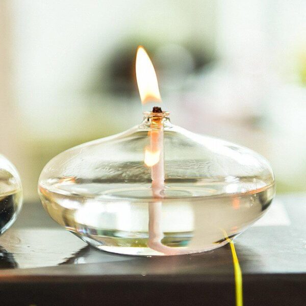 Oil lamp with a burning wick, made of clear glass, showcasing a modern take on traditional science decor.