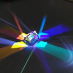 Colorful light dispersion prism creating vibrant rainbow beams on a dark background, ideal for science education and optical experiments.