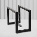 A modern Newton's Cradle with metallic balls and black frames demonstrating momentum transfer and energy conservation.