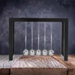 Newton's Cradle desktop physics toy with five shiny metal balls demonstrating conservation of momentum and energy. Perfect for science decor and educational purposes.