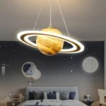 A modern planetary chandelier resembling a planet with rings, hanging from the ceiling, illuminating a space-themed bedroom.