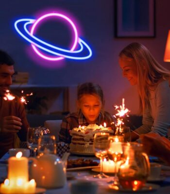 Neon planet decoration glowing above a birthday celebration with children and adults, creating a fun and educational atmosphere.