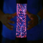 A person demonstrating a plasma lava lamp with colorful lightning-like electrical discharges inside a glass tube.