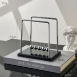 Elegant Newton's Cradle desktop toy with five metallic balls demonstrating physics principles. Perfect for science decor and educational purposes.