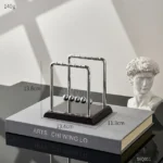 An elegant Newton's Cradle with five metallic balls demonstrating conservation of momentum and energy, perfect for science education and decor.