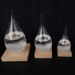 Three glass water droplet experiments on wooden bases, showcasing surface tension and fluid dynamics for educational science demonstrations.