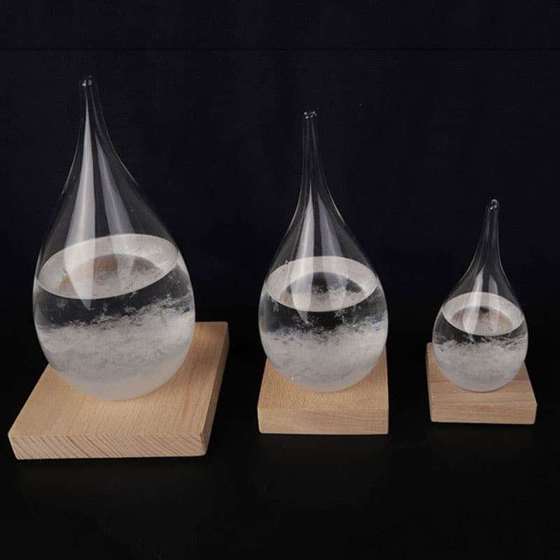 Three glass water droplet experiments on wooden bases, showcasing surface tension and fluid dynamics for educational science demonstrations.