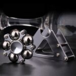 Close-up of a metallic magnetic fidget spinner with spherical balls, showcasing its intricate design and shiny surface.