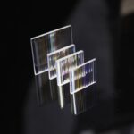 A set of four clear glass prisms with rainbow light dispersion effects, used for science experiments and educational demonstrations on light refraction and dispersion.