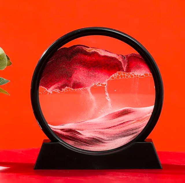 A mesmerizing lava lamp with flowing red and white wax inside a circular glass container, set against a vibrant orange background.