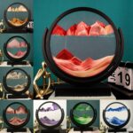 Artistic mountain landscape artwork in a circular frame, featuring layered mountain ranges in shades of red, pink, and orange, displayed on a black stand.