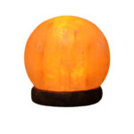 Salt lamp glowing with warm orange light, placed on a dark wooden base.