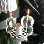 A creative coffee candle placed inside a glass sphere with a checkered base, surrounded by decorative glass orbs, creating a modern and artistic science-inspired decor piece.
