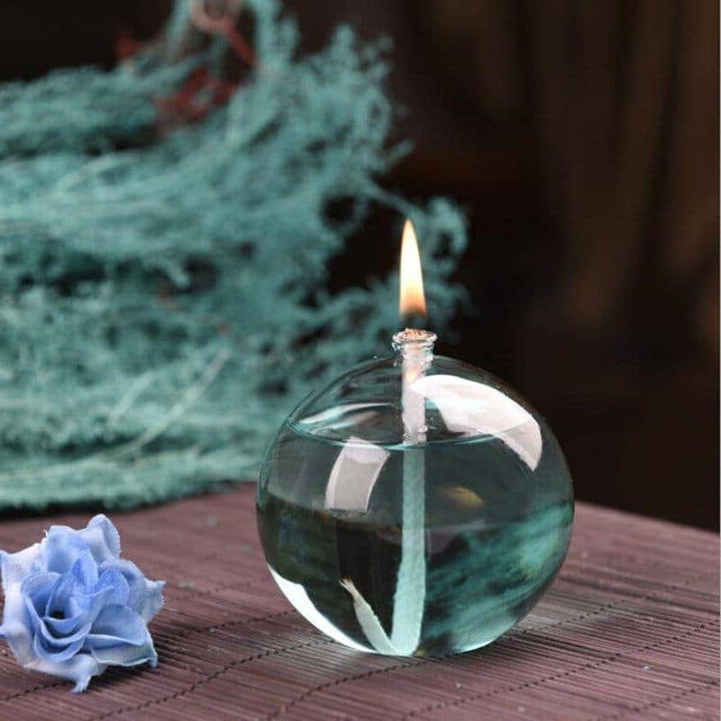 Elegant glass candle holder with a floating flame, surrounded by decorative blue flowers and textured background, perfect for science-inspired decor and educational displays.