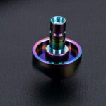 Colorful metallic spiral toy with rainbow hues on a black textured background, showcasing a modern, shiny design.