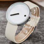 Modern minimalist watch with a sleek white strap and a distinctive dial featuring a single black hand and a small black dot, perfect for contemporary fashion.