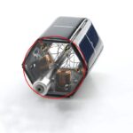Small solar-powered educational device with visible internal components, including copper coils and circuit parts, demonstrating solar energy conversion.