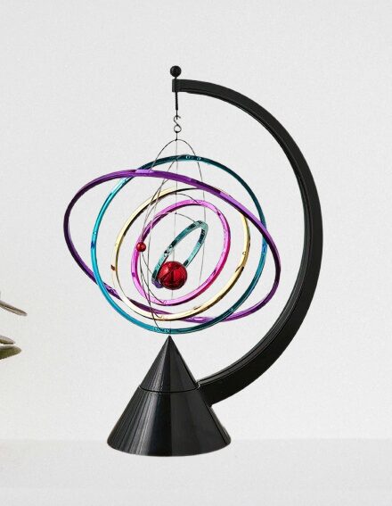 Elegant planetary model with colorful orbits and a red sphere representing a planet, mounted on a black stand.