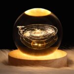 A detailed glass globe showcasing the solar system with planets labeled, including Neptune, Uranus, and Saturn, illuminated to highlight planetary orbits.